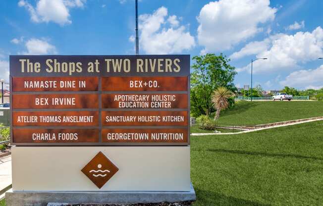 a sign for the shops at two rivers at the entrance of a park