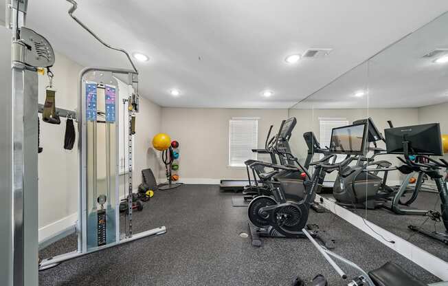 A gym with a variety of equipment including treadmills, stationary bikes, and weight machines.