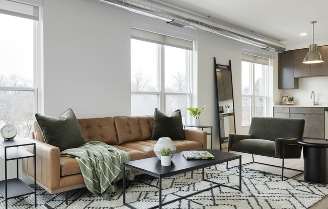 a living room with a brown leather couch and a black and white rug