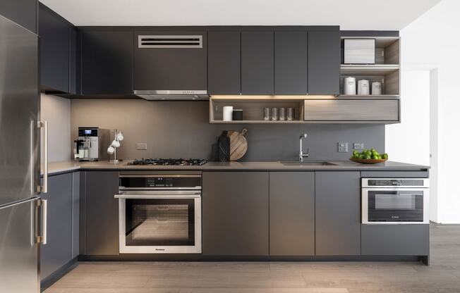 a kitchen with gray cabinets and stainless steel appliances