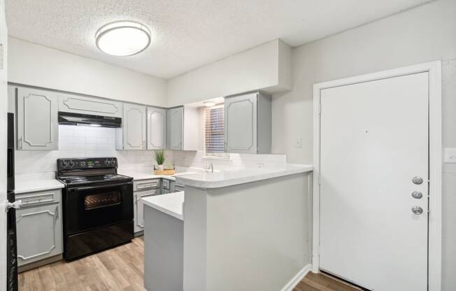 The Jackson apartment kitchen with light cabinets and black appliances