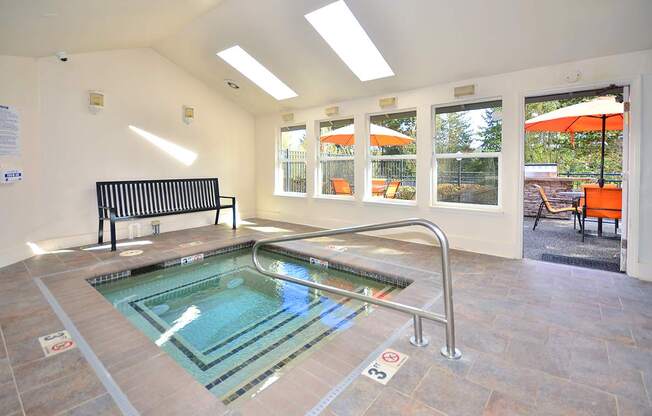 A small indoor pool with a bench and a window.