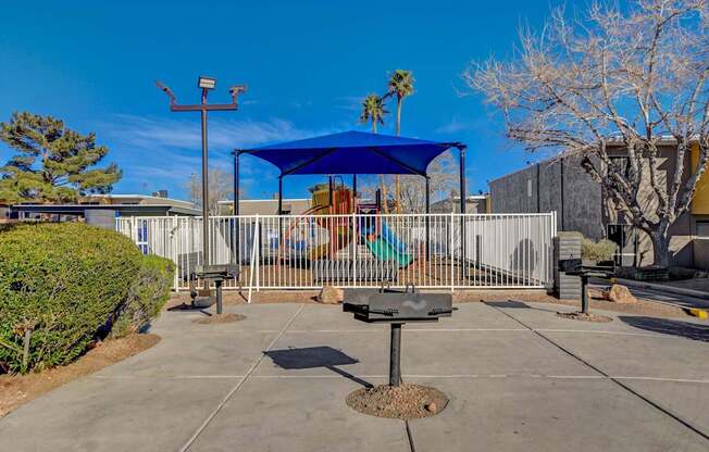 A playground with a blue canopy and a swing set.