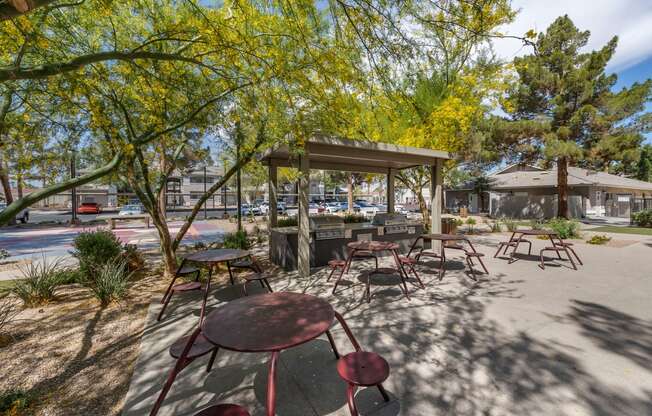 a picnic area with tables and chairs in a park at Paisley and Pointe Apartments, Las Vegas