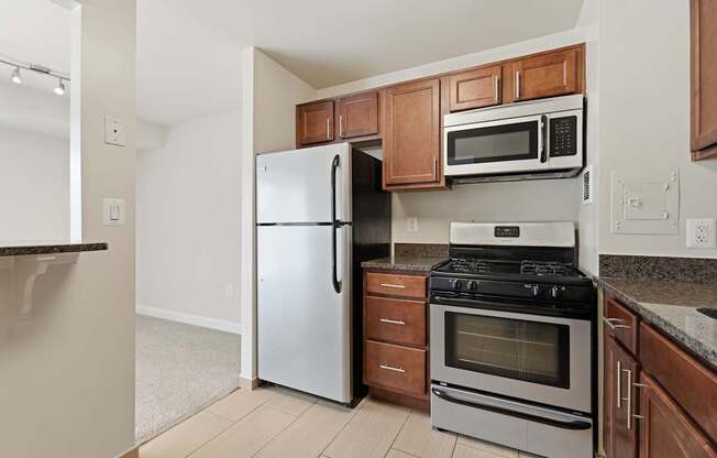 A kitchen with a white fridge, stainless steel oven, and microwave.
