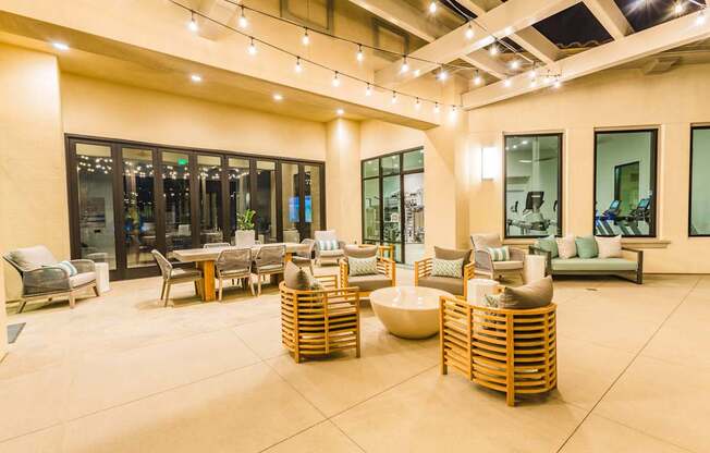 A spacious outdoor seating area with wooden furniture and string lights.