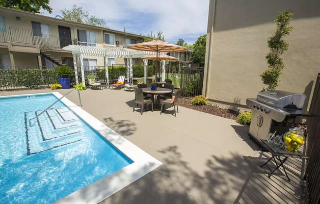 Pool area patio with a grill and a table and chairs