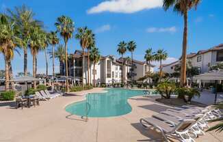 A pool surrounded by palm trees and sun loungers.