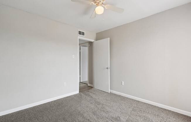 A room with a ceiling fan and carpeted floor.