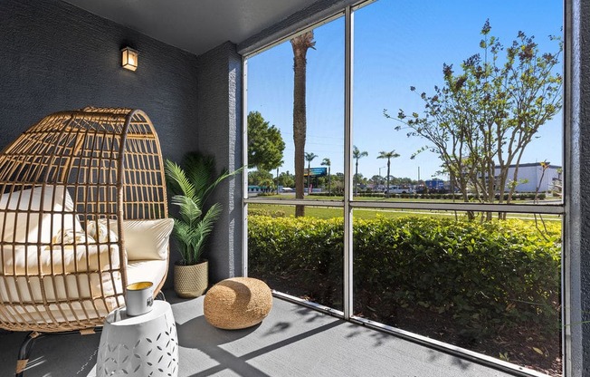 a room with a large window and a rattan chair