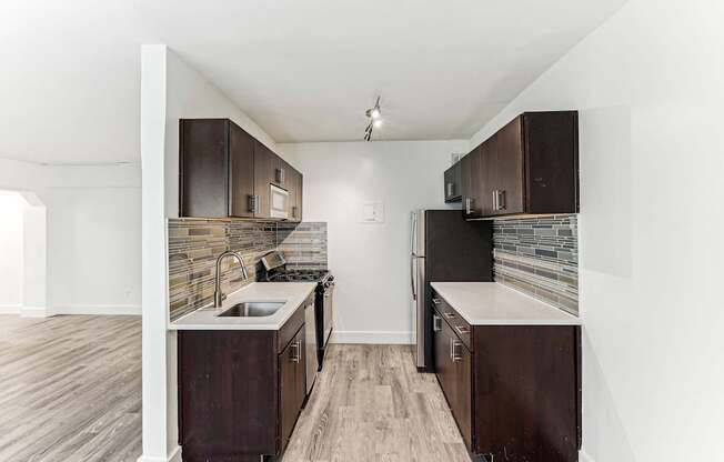 A kitchen with dark wood cabinets and a stone backsplash.