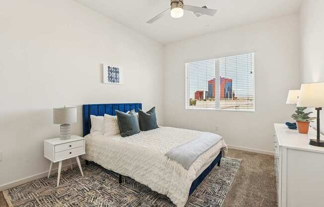 A bedroom with a bed, nightstand, and a window with blinds.