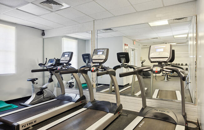 a gym with cardio equipment and mirrors in a break room