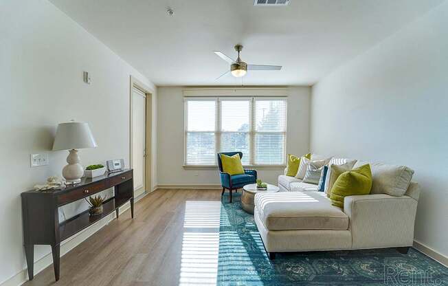 A living room with a couch, a table, a lamp, and a window.