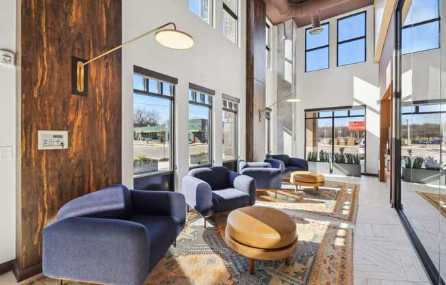 a lobby with blue chairs and tables and windows at Link Apartments® Broad Ave, Memphis, 38112