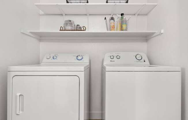 Two white front loading washing machines in a laundry room.