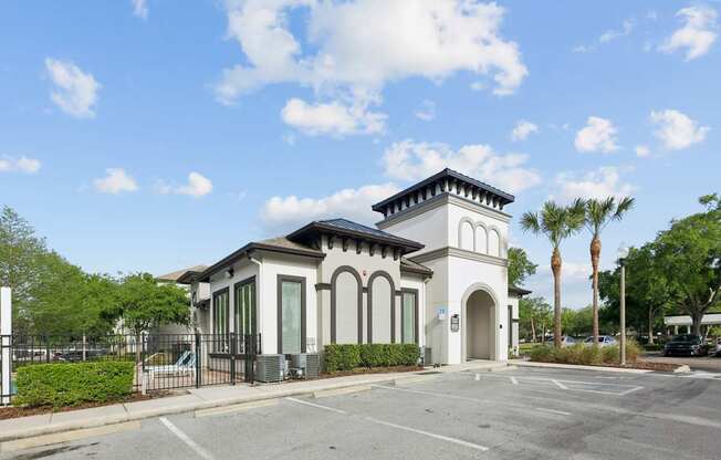 A small white building with a black roof and a black fence in front of it.