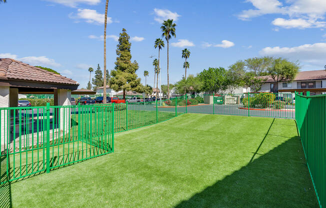 A green fenced area with a building and trees in the background.