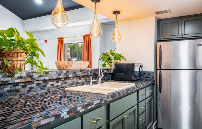 A kitchen with a black fridge and a black microwave.