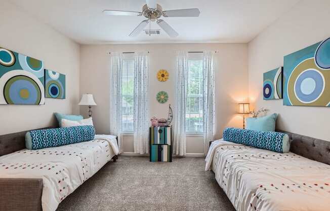 a bedroom with two beds and a ceiling fan