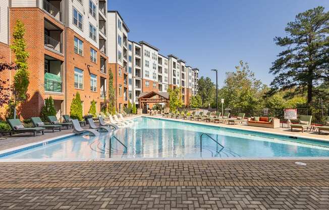 a swimming pool at an apartment building with a pool and lounge chairs