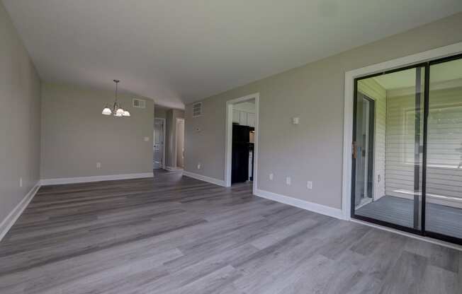 a empty living room with a sliding glass door to a balcony