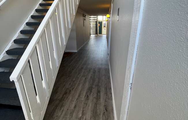 a look down the hallway of a house with hardwood floors and a staircase