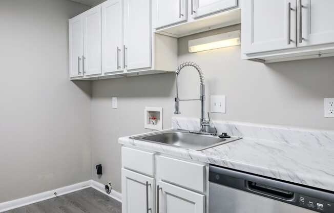 an empty kitchen with white cabinets and a stainless steel sink