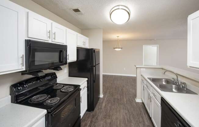 an empty kitchen with white cabinets and black appliances