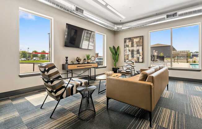 A living room with a striped chair, a brown couch, and a small table with a vase on it.