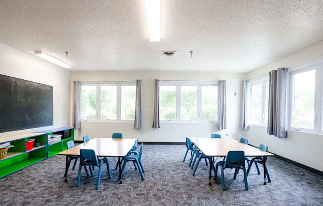 a classroom with tables and chairs and a chalkboard on the wall at Sutton Hill Apartments, Des Moines, IA, 50320