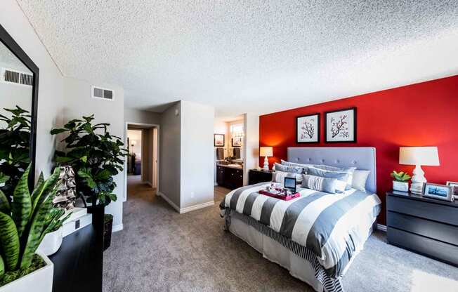 bedroom with dresser and bed with bathroom and hallway in background