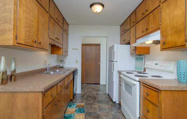 a kitchen with white appliances and wooden cabinets. Fargo, ND Country Club Apartments.