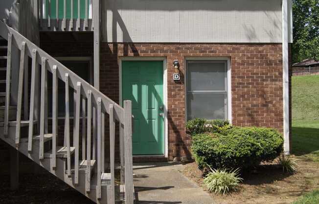a brick building with a green door and a staircase