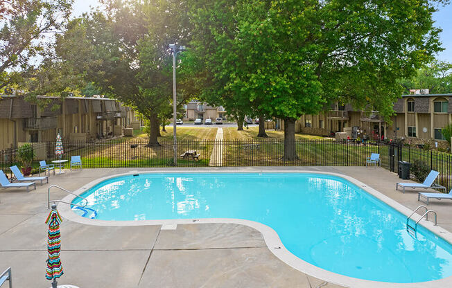 a swimming pool with chairs around it and trees