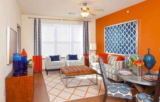 a living room with orange walls and a dining room with a table and chairs