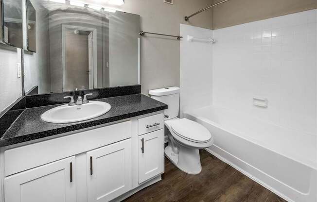 A white toilet sits in a bathroom with a black counter top.