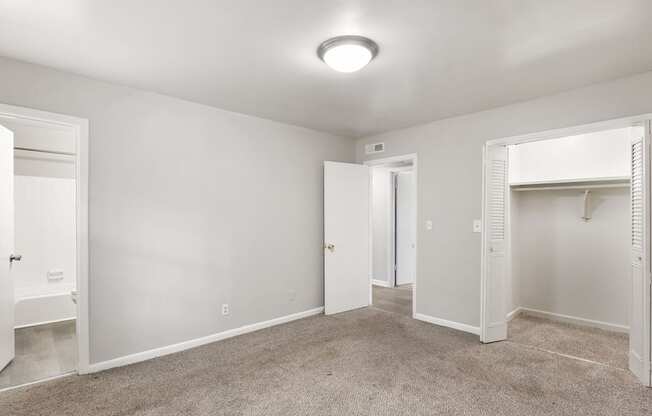 an empty bedroom with a closet and a door to a bathroom