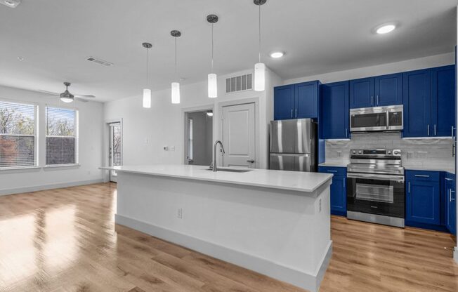 an empty kitchen with blue cabinets and a white counter top