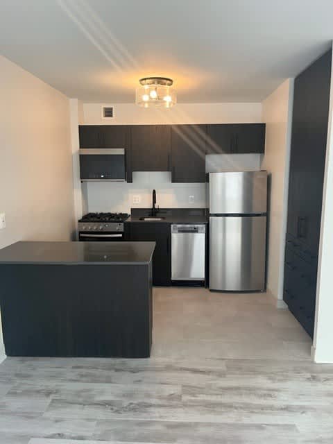 A kitchen with a black countertop and stainless steel appliances.
