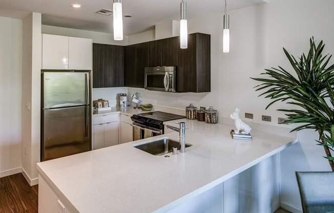 A modern kitchen with a white countertop and stainless steel appliances.