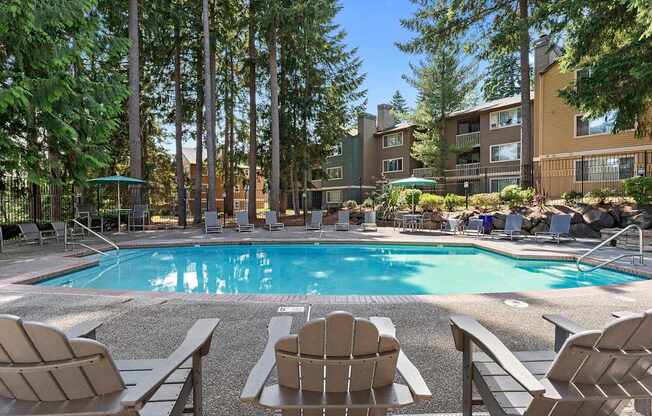 A pool surrounded by chairs and trees.