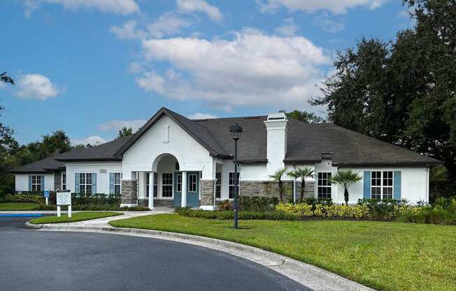 A white building with a black roof and a sign in front.