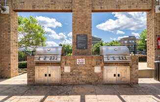 two bbq pits on the side of a brick building