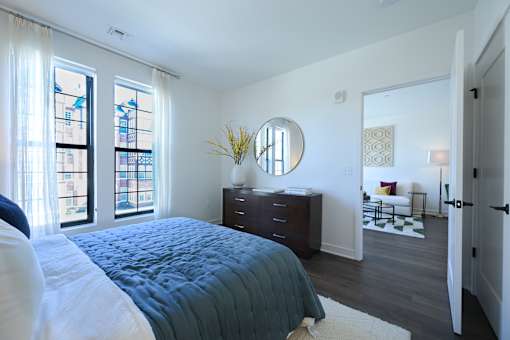 a bedroom with a bed and a dresser and a large window