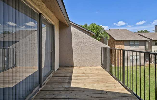 a balcony with a wooden deck and a glass sliding door