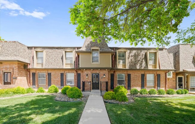 A row of houses with a tree in front.