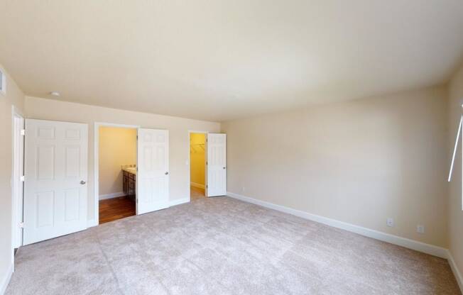 an empty living room with white doors and carpet