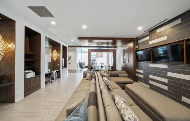 A modern living room with a long couch and a television on the wall.