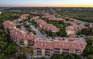 A sunset view of a large residential complex with multiple buildings and parking lots. at Bridge at Heritage Woods, Austin, Texas